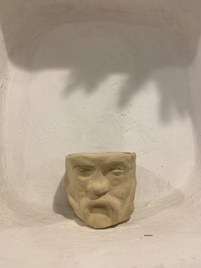 A small clay pot with a face on it